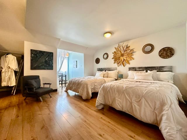 Bedroom with two beds, wood floors, and seating