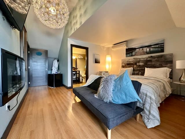 Bedroom suite with bed, seating, and vaulted ceiling